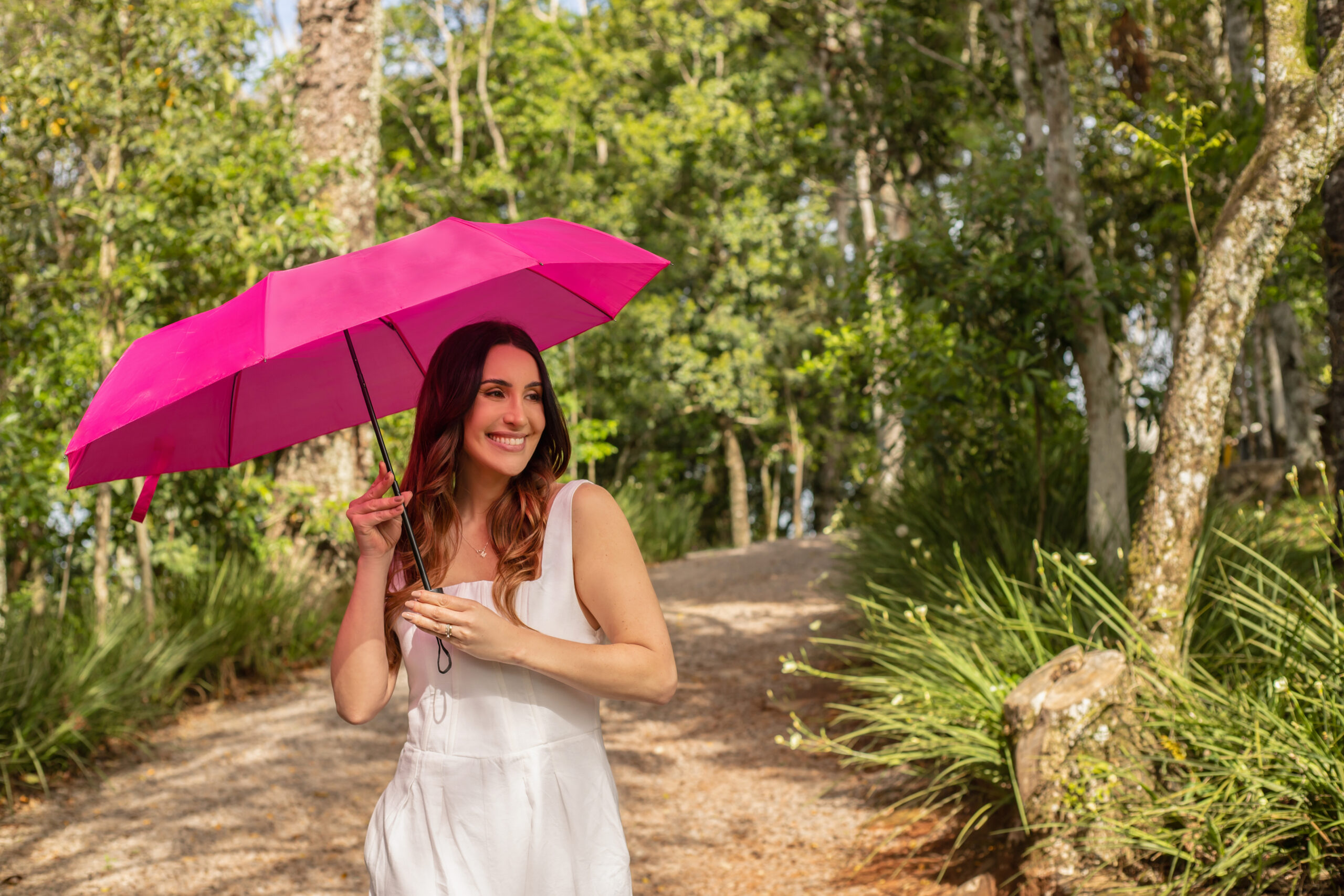 Mulher com guarda-chuva pink personalizado em trilha de mata, brinde da Florença para corridas e eventos esportivos ao ar livre